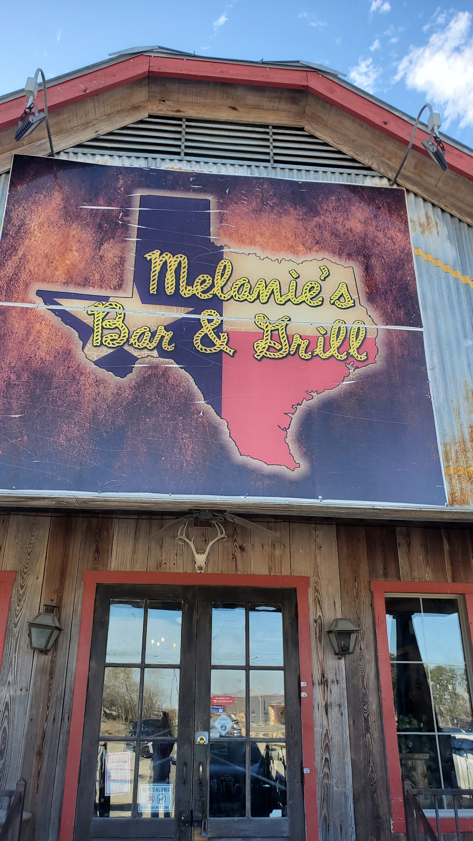 Melanie's Bar & Grill exterior sign with Texas flag mural